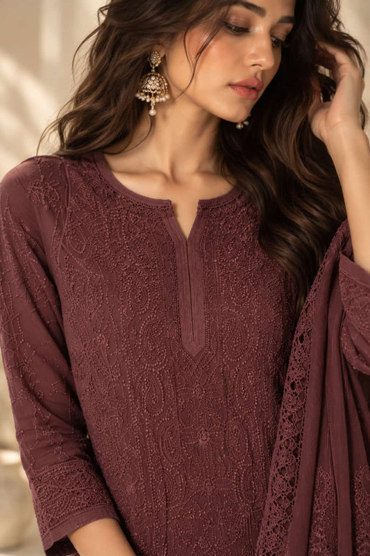 A woman wearing a deep plum lace embroidered kurta with a split neckline and matching draped fabric, styled with ornate gold earrings.