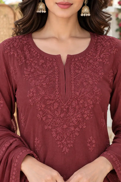A close-up of a woman wearing a maroon long-sleeve kurta with intricate floral embroidery around the split neckline and chest, paired with matching embroidered cuffs and a dupatta.