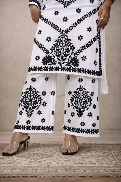 White chikankari kurti set with black floral embroidery worn with matching embroidered pants