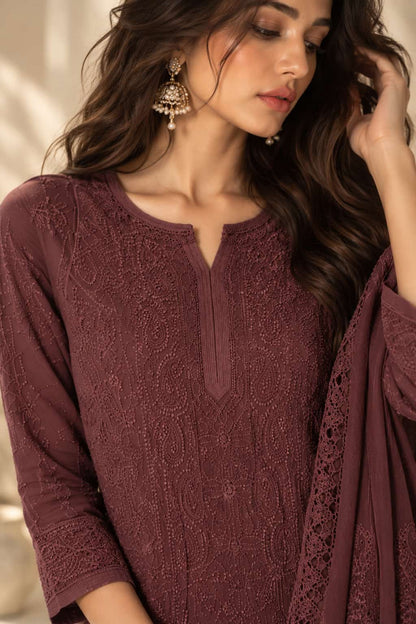 A woman wearing a deep plum lace embroidered kurta with a split neckline and matching draped fabric, styled with ornate gold earrings.