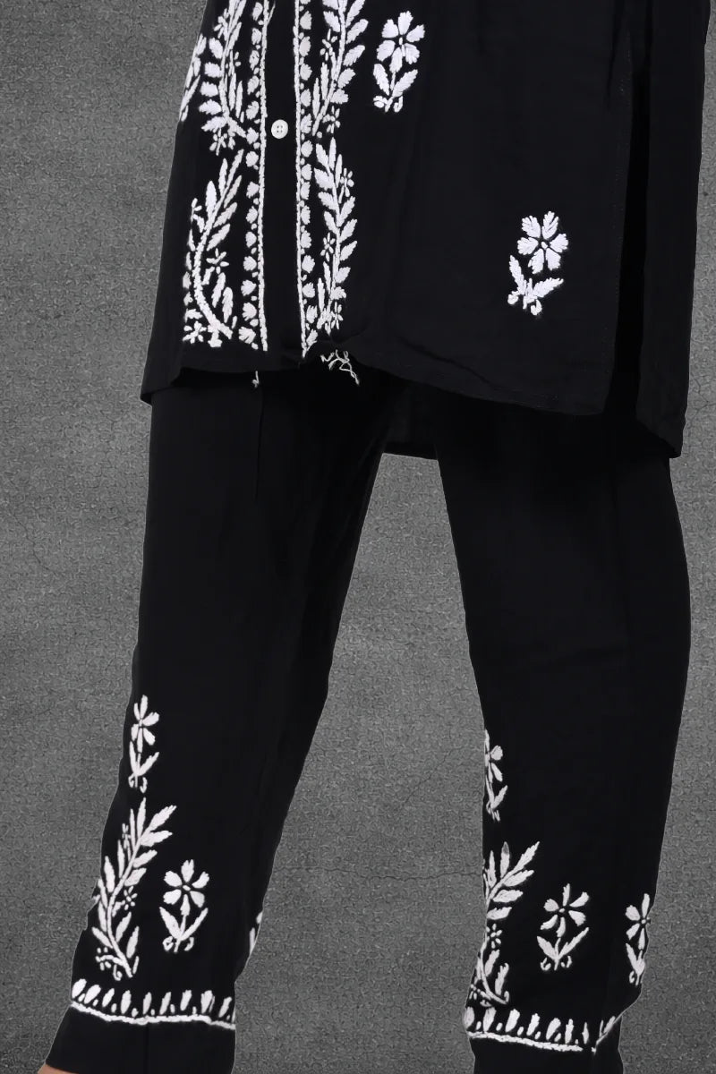 Women wearing black rayon cotton Chikankari set with intricate white thread embroidery in garden setting


